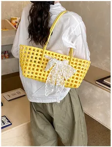 Détail du sac cabas en tricot ajouré jaune avec un nœud élégant en dentelle blanche