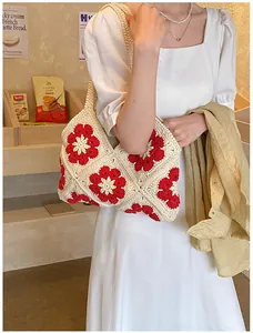 Detail of hand-crocheted cream shoulder bag featuring red floral embroidery accents