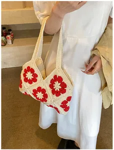Detailed macro view of handmade white crochet tote with red floral pattern and soft texture