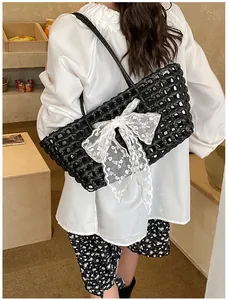 Détail du sac cabas tissé noir avec nœud en dentelle brodée de fleurs blanches sur la sangle