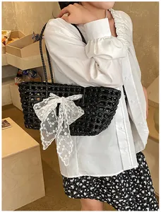 Détail d'un sac cabas tressé noir orné d'un nœud en dentelle blanche de style décontracté