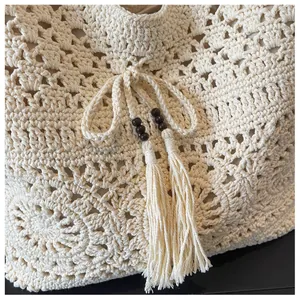 Detail of crochet tote bag with openwork floral pattern, wooden beads and long tassels