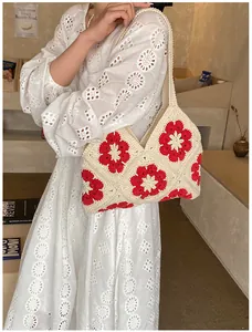 Detailed macro view of handmade granny square crochet shoulder bag with red floral patterns