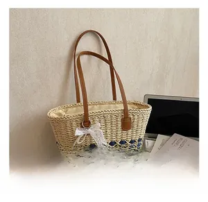 Detailed shot of straw tote with blue stripes, leather straps and pearl bow charm