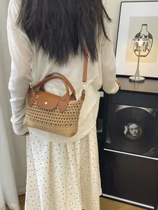 Minimalist straw woven tote bag with brown leather strap and metal buckle for beach use