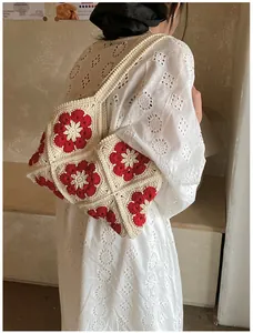 Close-up of handmade granny square crochet shoulder bag with red floral pattern detail