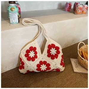 Close-up of crochet floral pattern on a beige and red woven shoulder beach bag