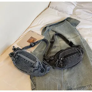 Detail of light blue and dark grey denim chest bags with zippers on white sheets