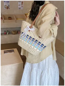 Detail of straw tote bag with blue wavy trim, lace bow, pearl, and leather strap
