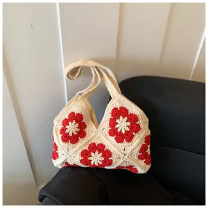 Close-up of handmade crochet bag with red flowers and beige bohemian woven texture