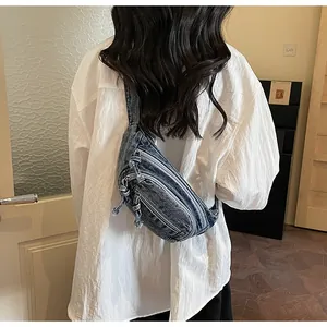 Rear view of a blue washed denim crossbody chest bag with multiple zipper compartments