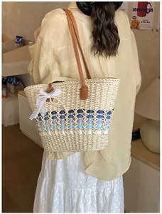 Detail of woven straw tote bag with gradient pattern, leather strap and lace accessory