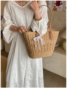 Detail of straw woven tote bag featuring white lace bow and elegant pearl pendant