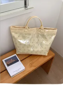 Detail of beige waterproof jelly tote bag featuring floral hollow pattern and PVC finish