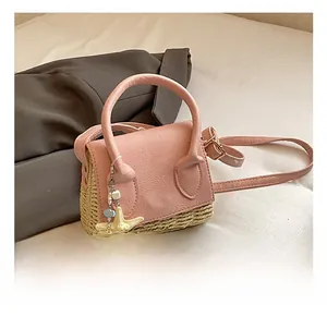Detail of pink leather and straw crossbody bag with starfish charm on white fabric