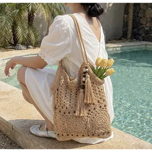 Dettaglio ravvicinato della borsa tote intrecciata con nappe e perle di legno in piscina
