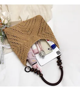 Detail view of khaki crochet knit bag with wooden beads and spacious interior storage