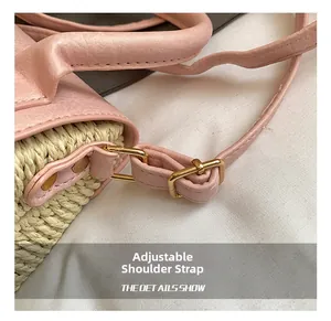 Detail showing pink leather strap with gold buckle and woven straw texture on the bag