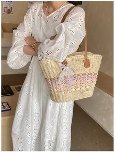 Close-up of woven straw tote bag with pink stripes and lace bow on a white dress