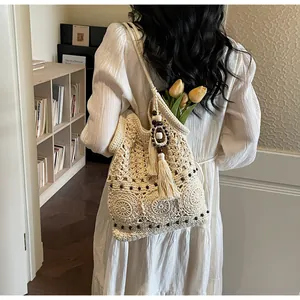 Dettaglio della borsa tote beige tessuta a mano con motivi floreali e perline nere decorative