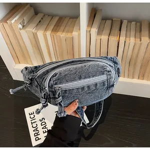 Detailed view of denim fanny pack featuring three zippered layers and adjustable strap
