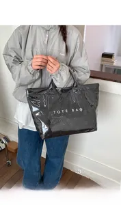 Close-up of black glossy tote bag with laser-cut floral patterns and white logo lettering