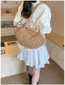 Detail of woven straw fan-shaped bag with wooden handle and braided shoulder strap