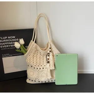 Dettaglio della borsa tote in crochet crema con perline in legno e nappe boho