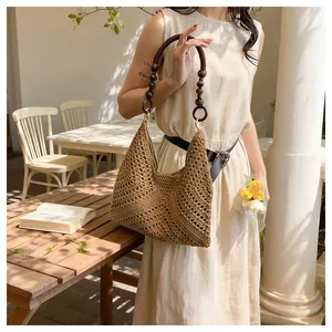Detail of hand-woven hollow pattern and round dark wood bead handle on a brown beach bag