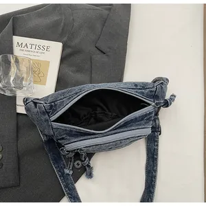 Top view of denim crossbody bag showing zipper closure, inner lining, and raw edge texture