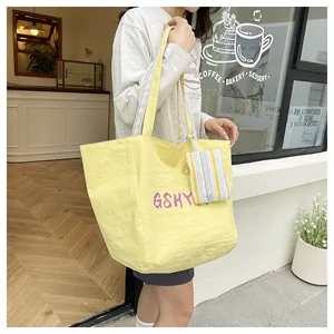 Detalle del bolso tote de nailon amarillo con estampado GSHY morado y mini bolsa a rayas
