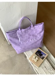 Detail of purple waterproof tote bag featuring laser-cut floral patterns and gloss finish