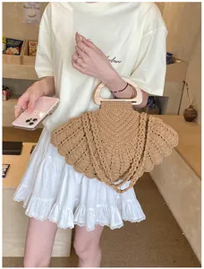 Detail of a brown woven cotton shoulder bag with semicircular wooden handles