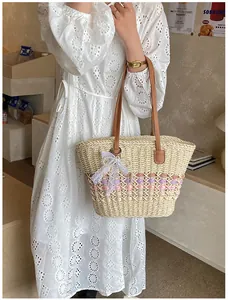Detail of woven straw tote bag featuring colorful wave patterns and lace bow accessory