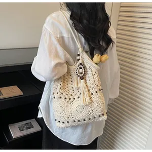 Dettaglio della borsa tote all'uncinetto con motivi floreali, perle in legno e nappine