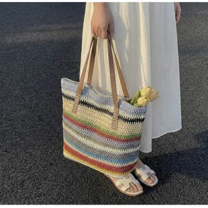 Detailed texture of rainbow stripe woven beach tote bag held by a woman in white dress