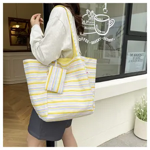Detalle del bolso tote de punto a rayas con mini monedero a juego y forro interior amarillo