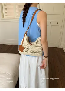 Detail of crochet hobo bag with brown leather strap and flower charm on shoulder