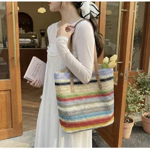 Rainbow striped woven tote bag with brown leather straps held by a model in a white dress