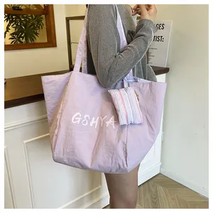 Detalle del bolso tote de nylon lavanda con letras blancas y un colgante a rayas