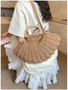 Detail of fan-shaped woven handbag with wooden handle and intricate crochet texture