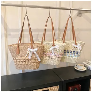 Straw tote bags with leather handles and lace bows in three colors on a hanger