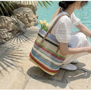 Detail of colorful rainbow woven straw tote bag with brown leather handles in a poolside setting