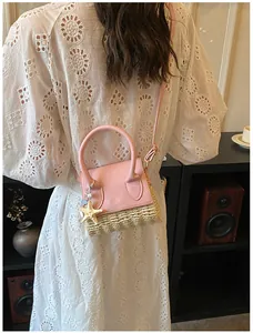 Close-up of mini straw bag with pink leather flap and starfish charm on lace dress