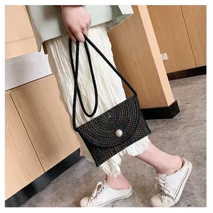 Détail d'un sac en paille tissé avec motif zigzag coloré et boucle ornée d'une grosse perle