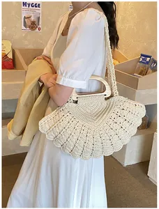 Detail of hand-woven shell shaped cotton bag with circular wooden handles and long strap