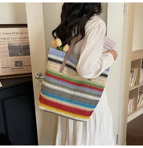Detail of colorful rainbow striped straw tote bag featuring brown leather shoulder straps