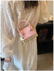 Detailed view of mini straw crossbody bag with pink leather flap and star pendant charm