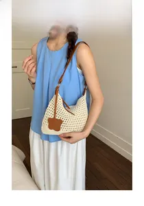 Close-up of hand-woven mesh tote bag with brown leather strap and flower pendant detail