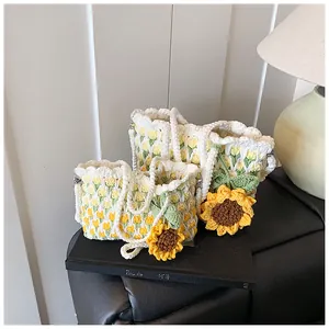 Makrodetail der handgefertigten Häkel-Tulpentasche mit gestrickten Sonnenblumen auf Büchern